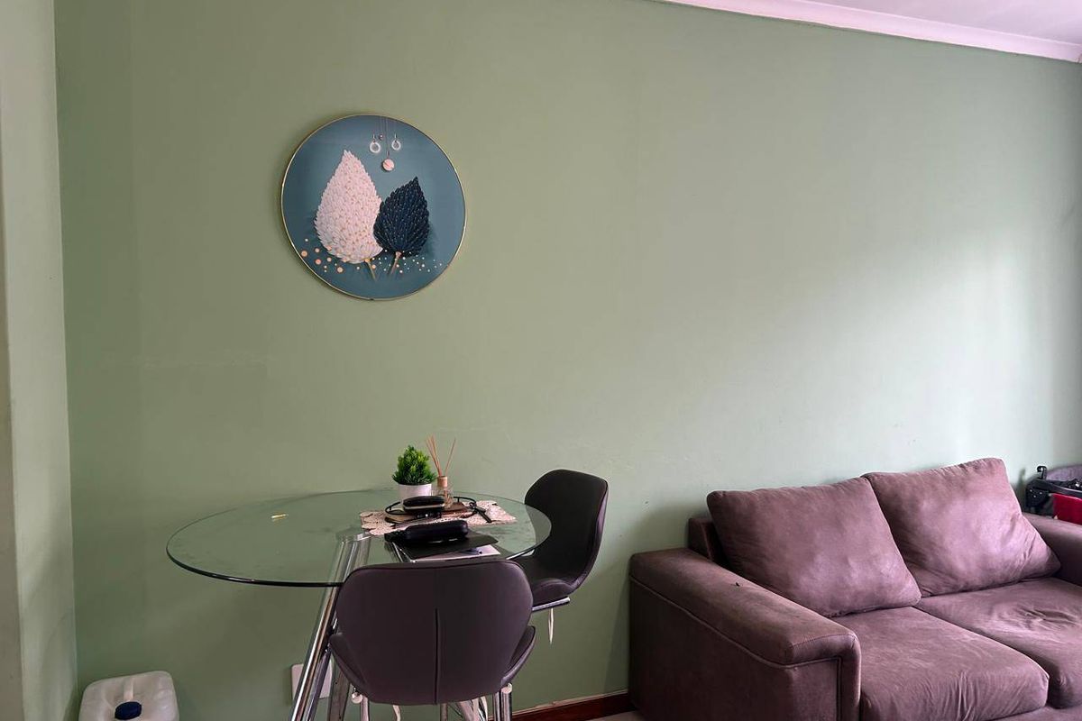 A living area featuring tiled flooring and neutral green walls, providing a functional space for relaxation and dining.