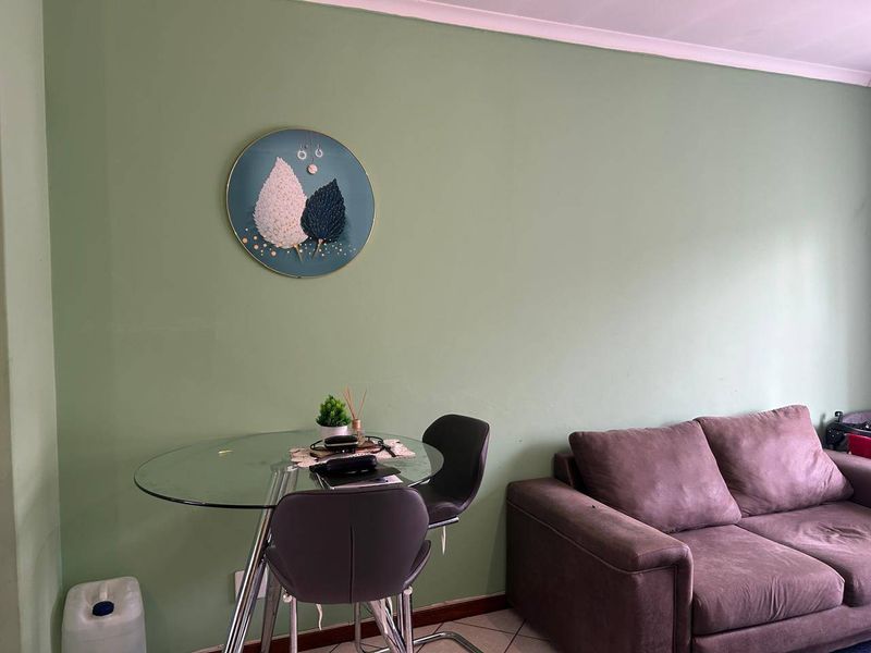A living area featuring tiled flooring and neutral green walls, providing a functional space for relaxation and dining.