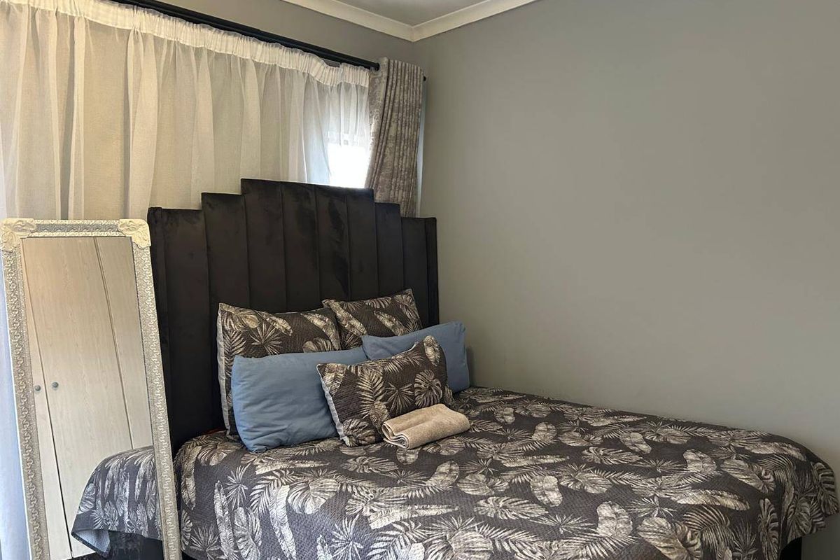 A cozy bedroom featuring neutral grey walls, coving, and a curtain rod setup.