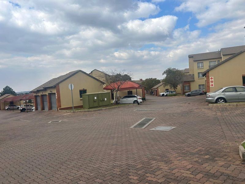 Exterior view of the apartment complex featuring a paved driveway, multiple garage units, and covered parking bays.