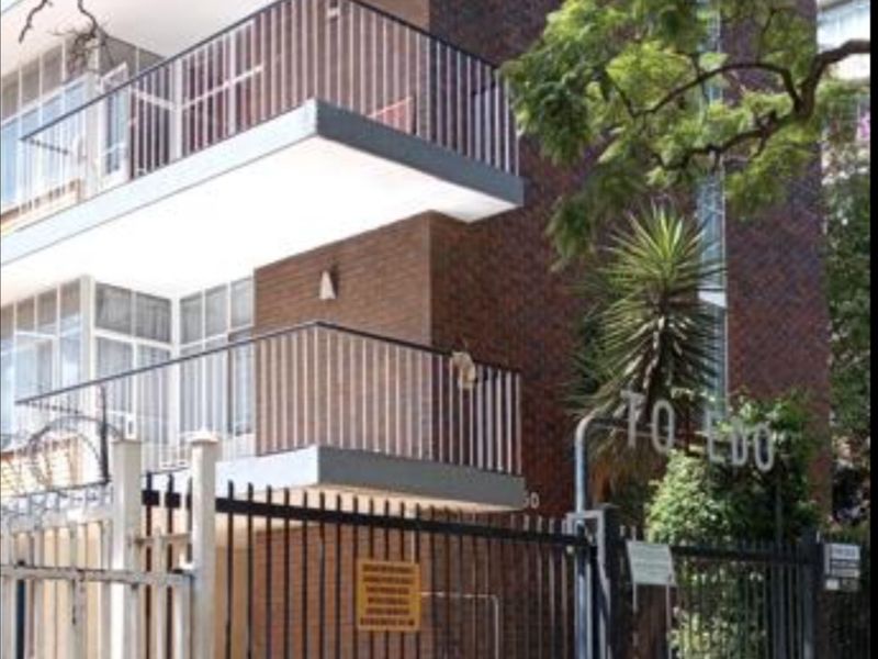 Front view of the Toledo apartment building featuring a brick facade, multiple balconies with metal railings, and a secure gated entrance.