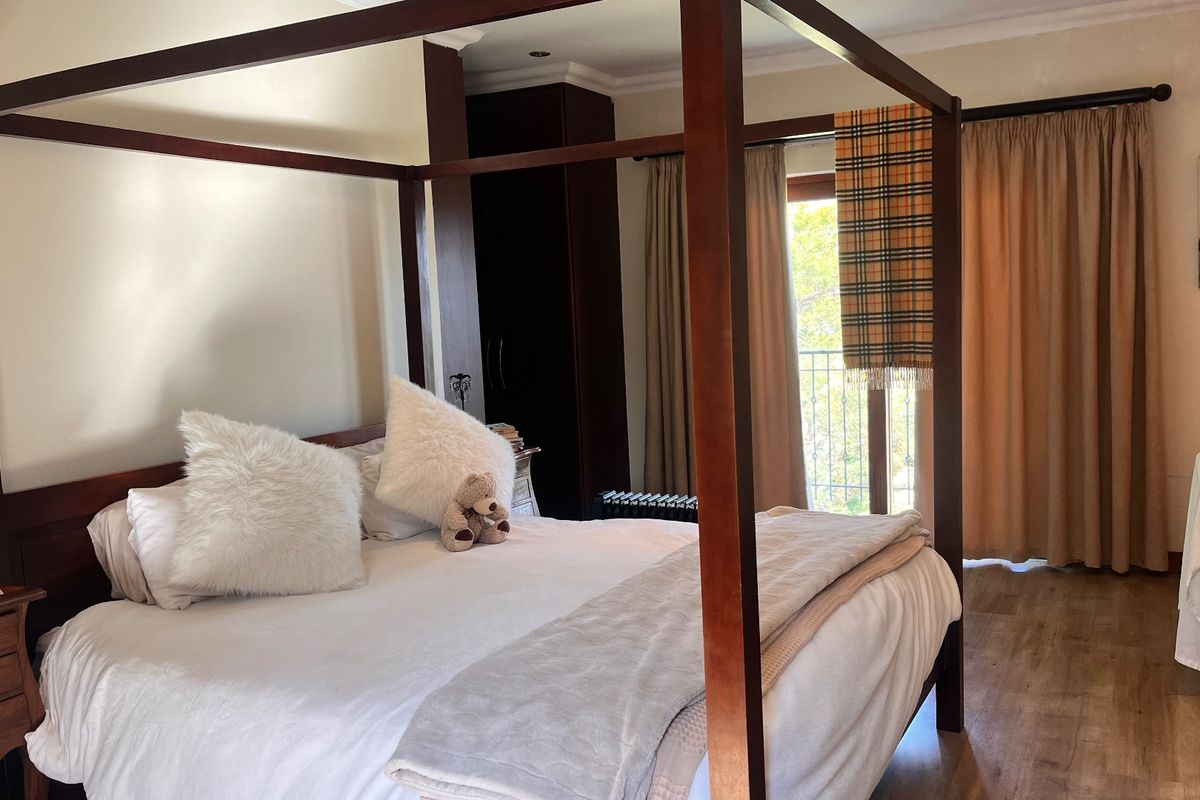 Spacious bedroom featuring laminate flooring, built-in cupboards, and direct access to a private balcony through sliding doors.