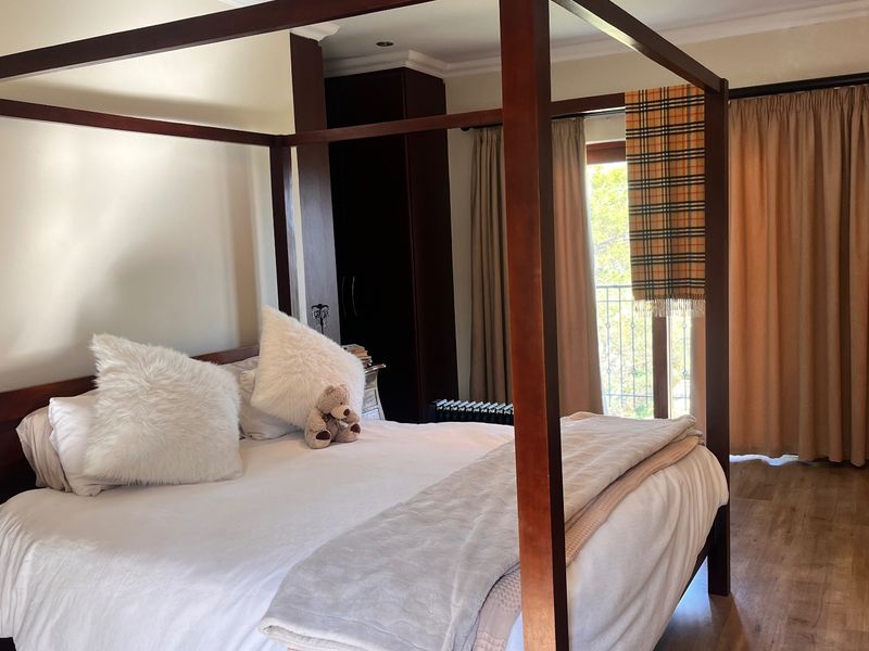 Spacious bedroom featuring laminate flooring, built-in cupboards, and direct access to a private balcony through sliding doors.