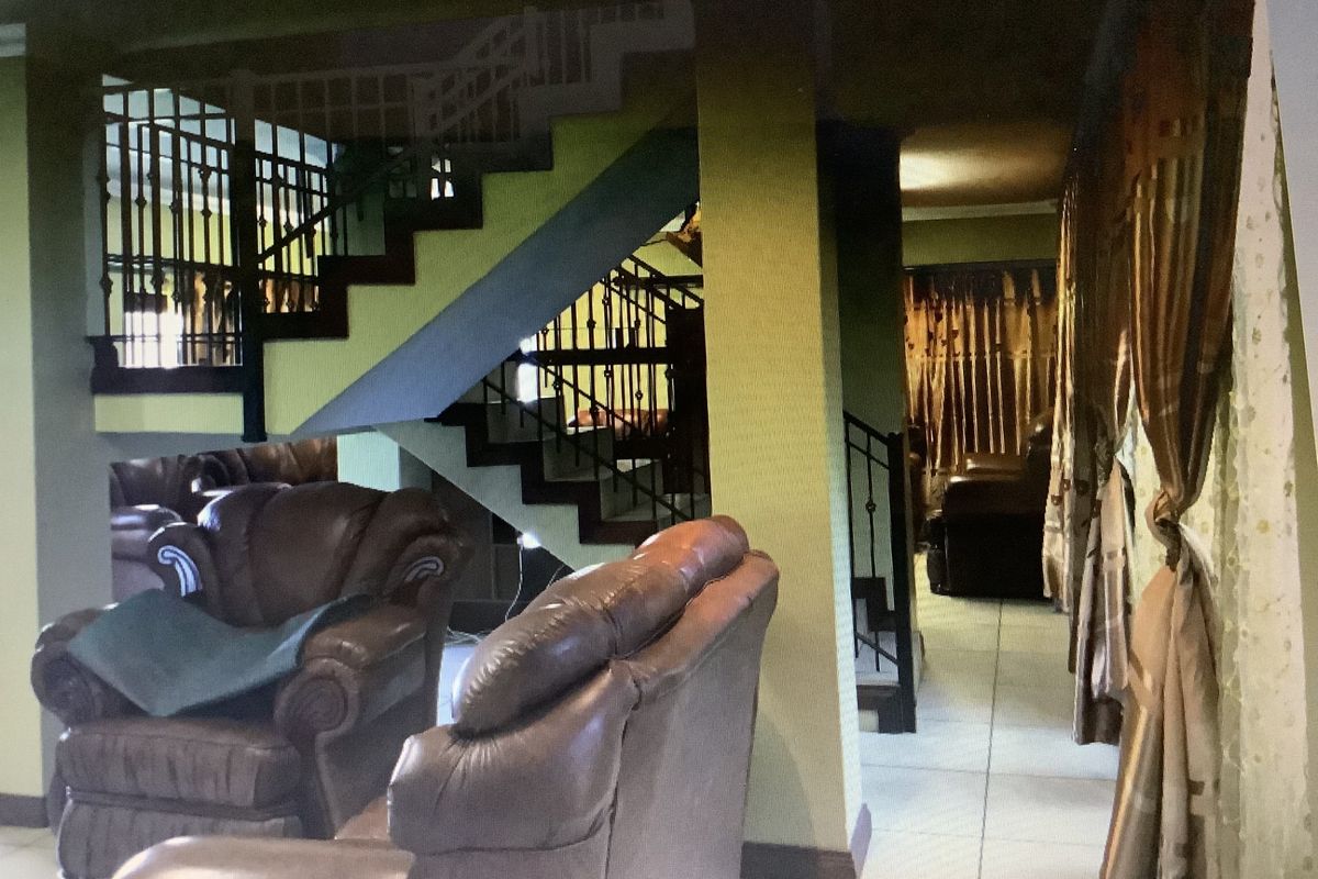 Living area featuring a prominent staircase with wrought iron balustrades and tiled flooring, connecting to adjacent living spaces.