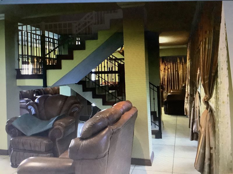 Living area featuring a prominent staircase with wrought iron balustrades and tiled flooring, connecting to adjacent living spaces.