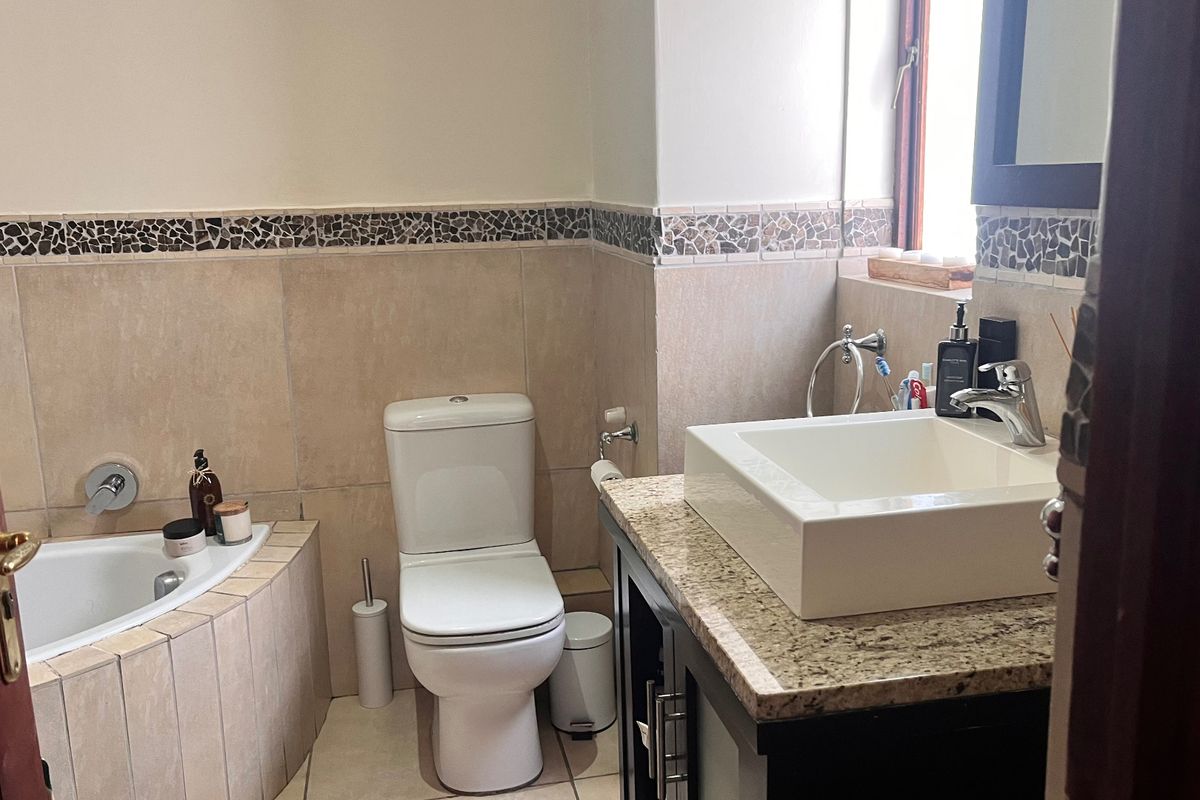 A functional bathroom featuring a built-in bathtub, a modern vessel sink on a granite vanity, and decorative mosaic tile accents.