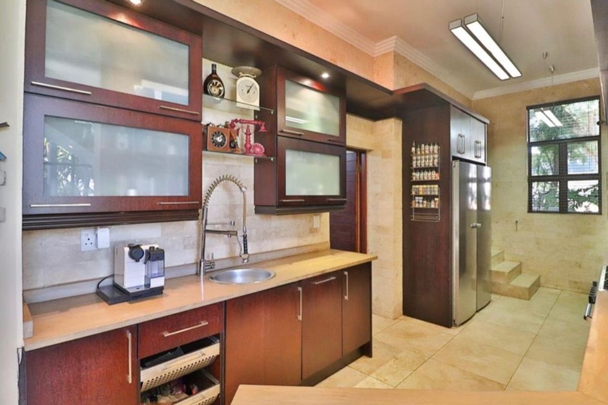 A well-appointed kitchen featuring dark wood cabinetry, stone tile finishes, and modern lighting, offering a functional and stylish culinary workspace.