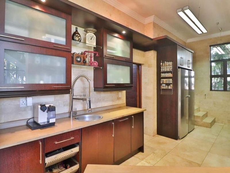 A well-appointed kitchen featuring dark wood cabinetry, stone tile finishes, and modern lighting, offering a functional and stylish culinary workspace.