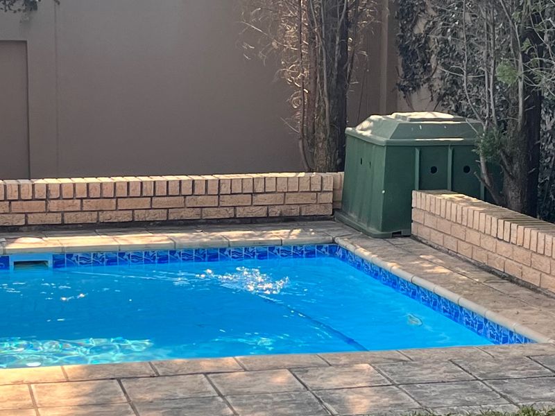 A private swimming pool area featuring a paved surround and low brick retaining walls, providing a functional outdoor space.