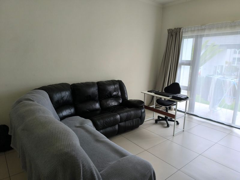 A living room area featuring neutral tiled flooring and a large sliding glass door providing access to the exterior.