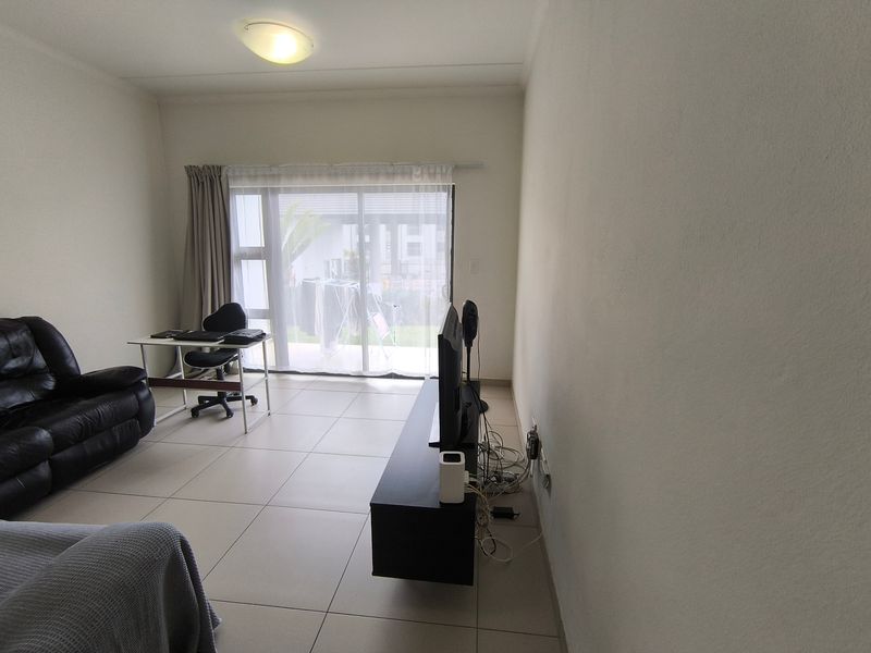 A living room featuring tiled flooring and a sliding glass door providing access to the exterior.