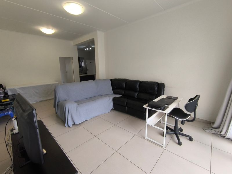 A spacious living area featuring neutral tiled flooring and simple ceiling lighting, offering a clean and functional layout for comfortable daily living.