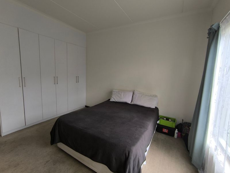 A functional bedroom featuring a large wall of built-in cupboards and neutral wall finishes, providing ample storage space.