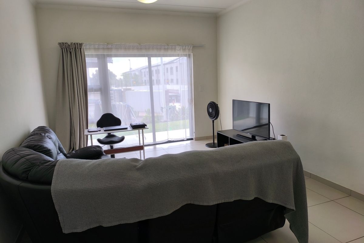 A living room featuring tiled flooring and a large sliding glass door providing natural light and access to the exterior.