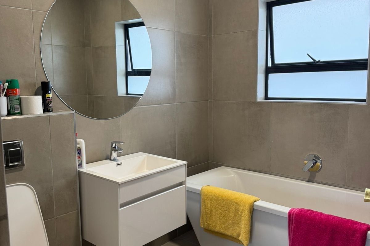 Modern bathroom featuring a wall-mounted vanity, freestanding bathtub, wall-hung toilet, and neutral floor-to-ceiling tiling.