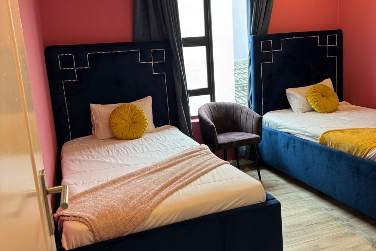 A well-maintained bedroom featuring laminate flooring, recessed downlighting, and an aluminium-framed window.