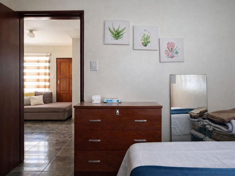 A bedroom featuring tiled flooring and a doorway leading to an adjacent living area with a neutral color palette.