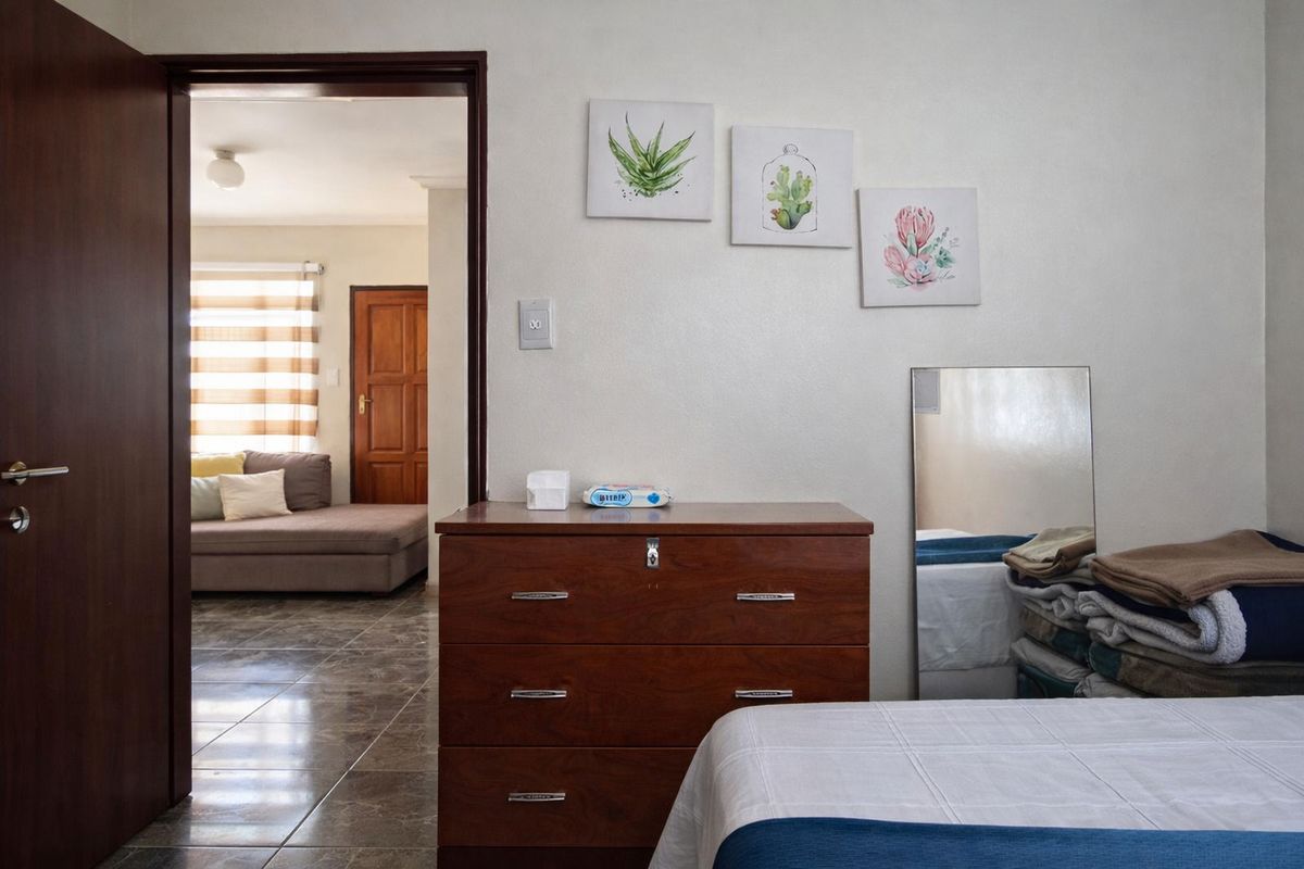 A bedroom featuring tiled flooring and a doorway leading to an adjacent living area with a neutral color palette.