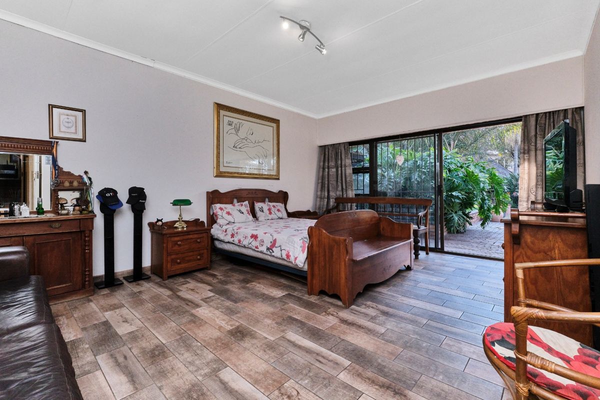 Spacious bedroom featuring wood-look tile flooring and large sliding glass doors providing direct access to the garden area.