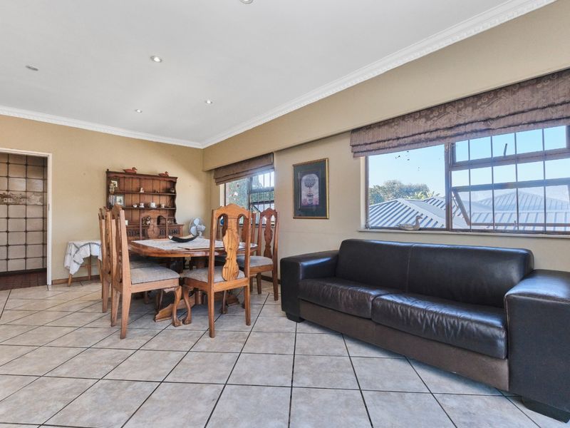 Open plan living and dining area featuring tiled flooring, recessed downlighting, and large windows with aluminium frames.