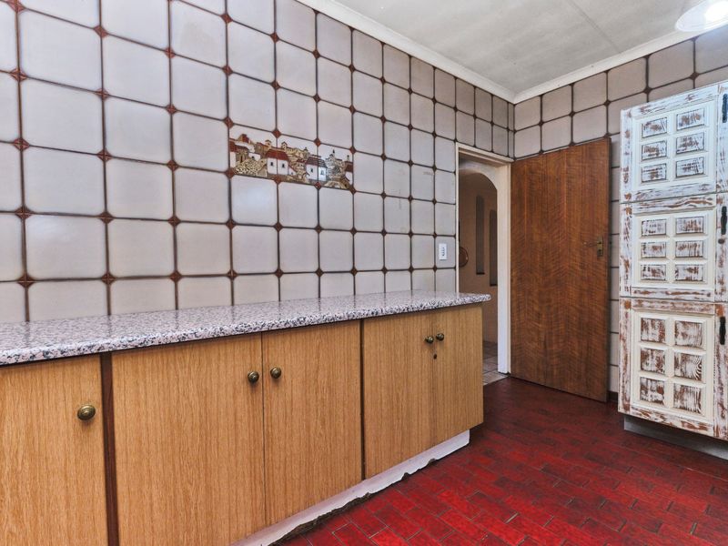 A dated kitchen featuring wood-look cabinetry, granite-effect countertops, and distinctive wall tiling, offering potential for a modern renovation.