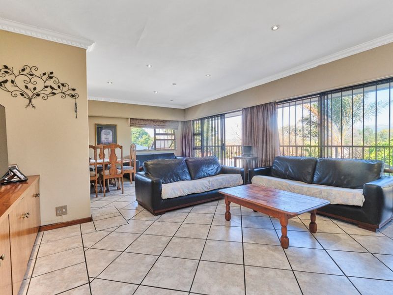 Spacious open-plan living and dining area featuring tiled flooring, recessed lighting, and large sliding glass doors leading to an outdoor balcony.