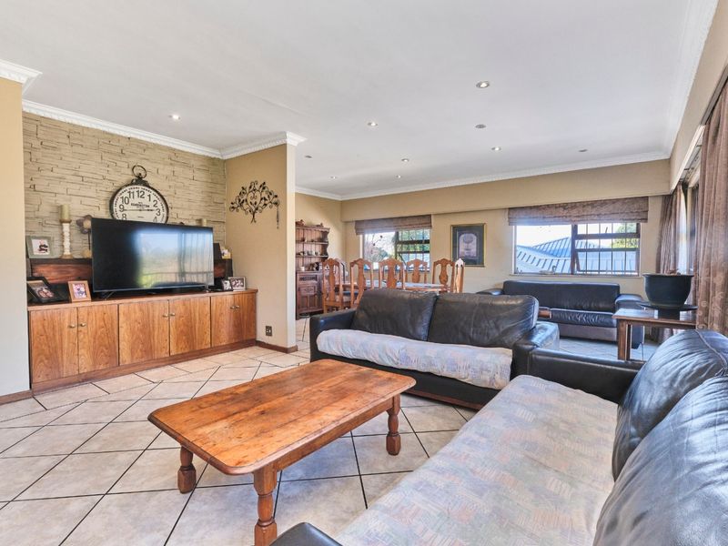 Spacious open-plan living and dining area featuring tiled floors, a stone feature wall, built-in cabinetry, and recessed downlighting.
