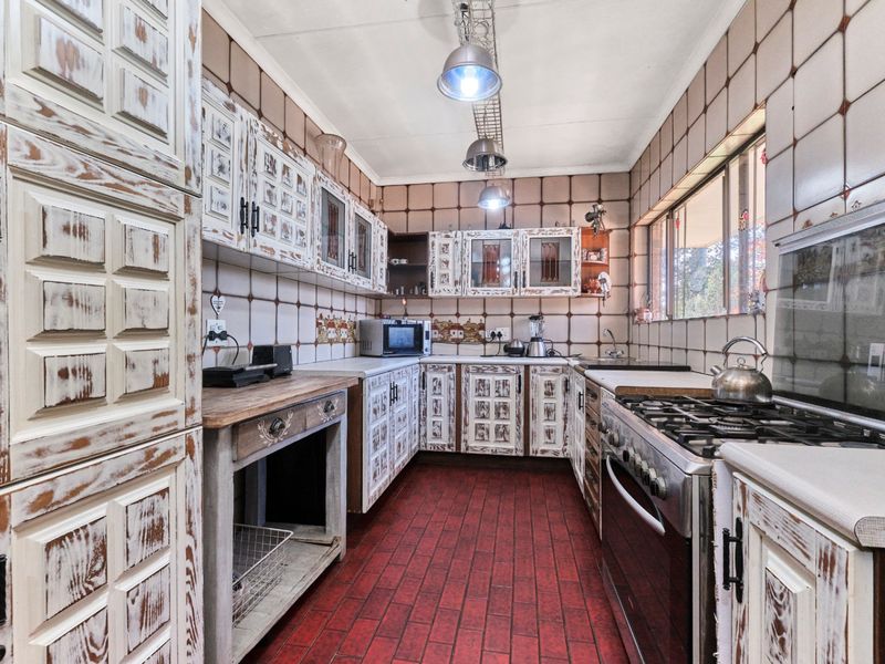 A dated kitchen featuring rustic-style cabinetry, tiled walls and flooring, and a gas stove, offering significant potential for a modern renovation.