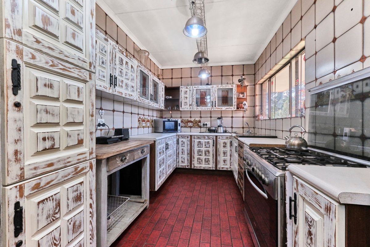 A dated kitchen featuring rustic-style cabinetry, tiled walls and flooring, and a gas stove, offering significant potential for a modern renovation.