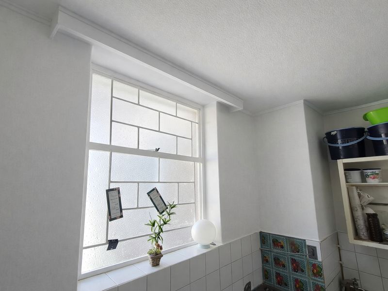 A kitchen area featuring a large glass block window and decorative tiled wall accents, providing a functional space with classic finishes.
