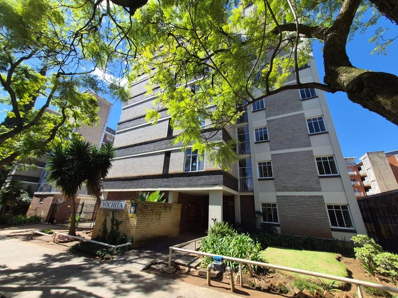 Front elevation of the Wichita apartment building featuring a brick facade, landscaped garden area, and secure entrance.