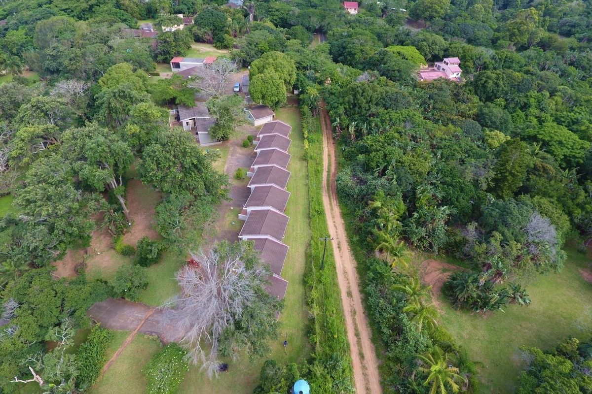 Aerial view of a residential property complex featuring multiple units with tiled roofs, surrounded by extensive mature trees and greenery.