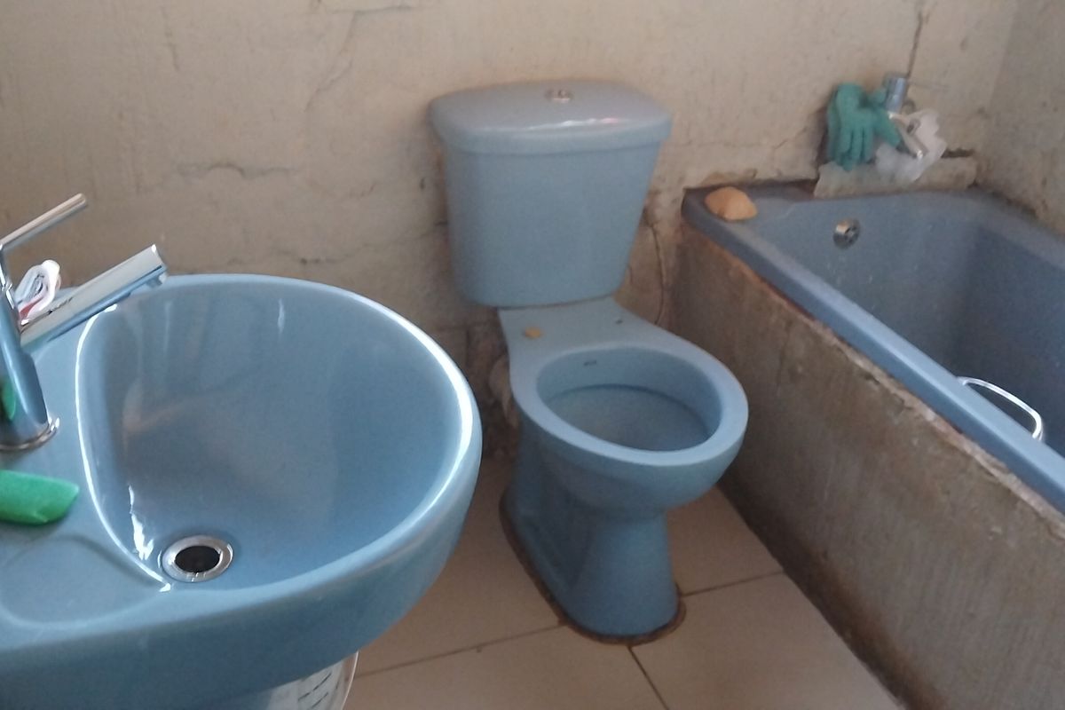 A dated bathroom featuring blue sanitaryware, including a basin, toilet, and bathtub, requiring significant cosmetic renovation and wall repairs.