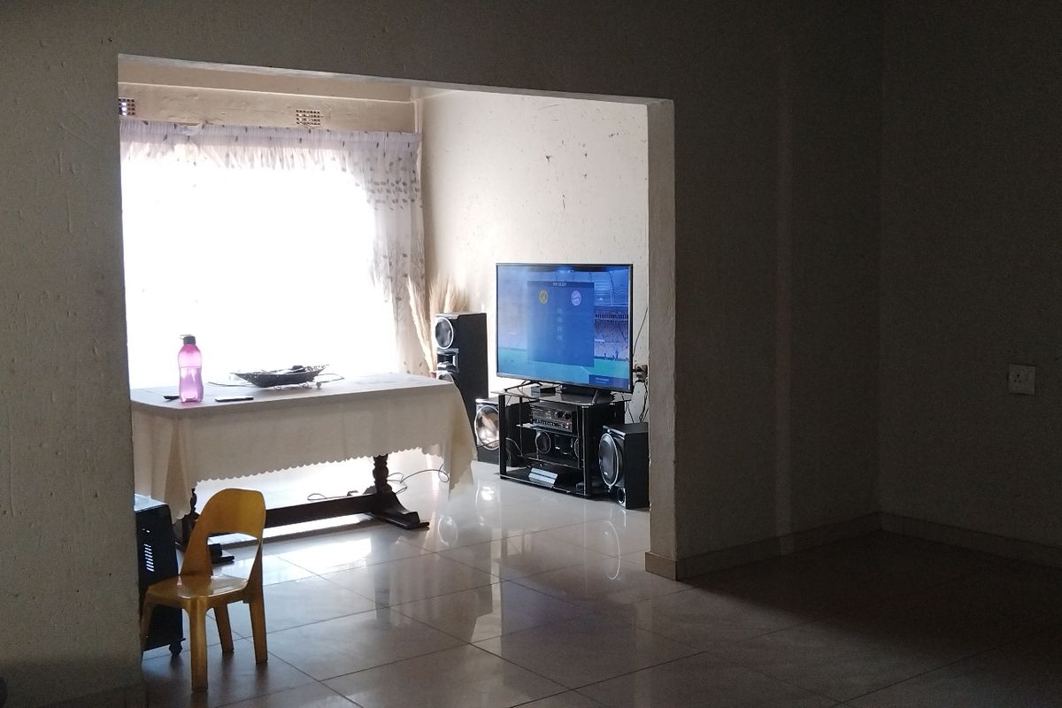 A living area featuring tiled flooring and a large window, providing natural light to the space.