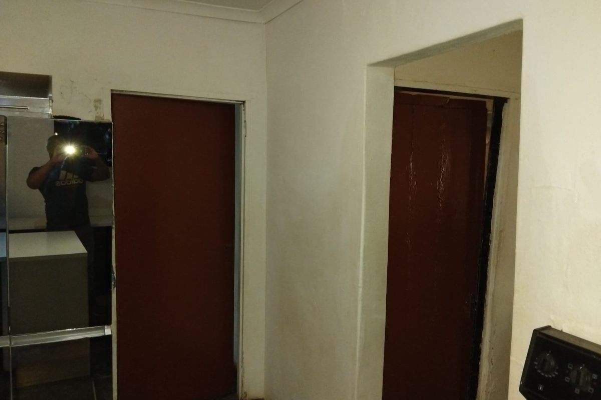 A simple interior hallway featuring plain white walls and two internal doors, requiring cosmetic updates to improve the overall finish.