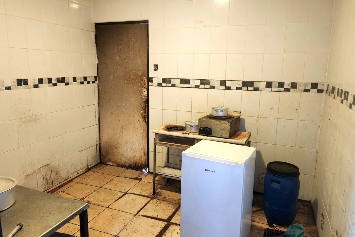 A utilitarian kitchen space featuring tiled walls and flooring, currently requiring significant cleaning and refurbishment to restore functionality.