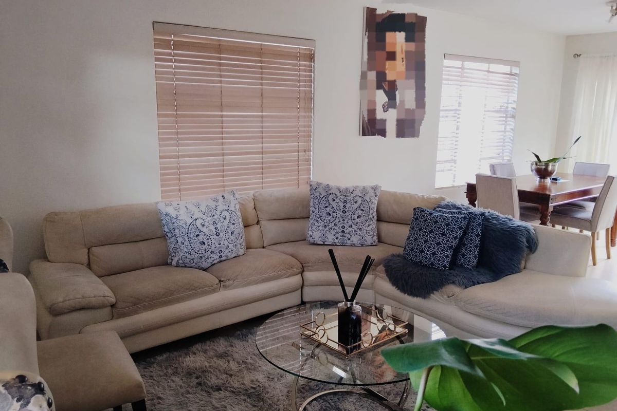 A bright and comfortable living room area featuring large windows with fitted venetian blinds, providing ample natural light to the space.