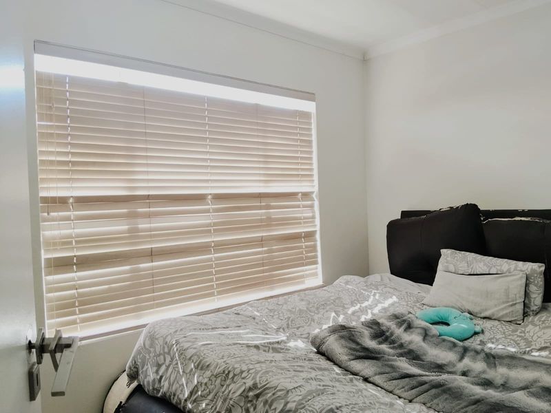 A bedroom featuring neutral walls and fitted venetian blinds, providing a simple and functional space.