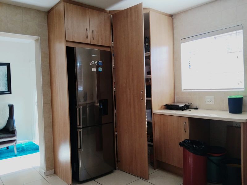 A functional scullery area featuring built-in wooden cabinetry, laminate countertops, and tiled finishes, providing additional storage and prep space adjacent to the main living area.