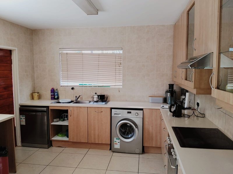 Functional kitchen featuring laminate cabinetry, tiled backsplash, built-in oven, electric hob, and integrated appliance spaces, offering a practical layout for daily use.