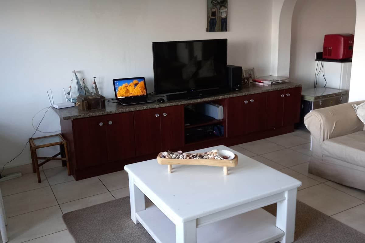 Living room featuring built-in cabinetry with granite countertops, tiled flooring, and an arched entryway. Visible water damage on the wall requires attention.