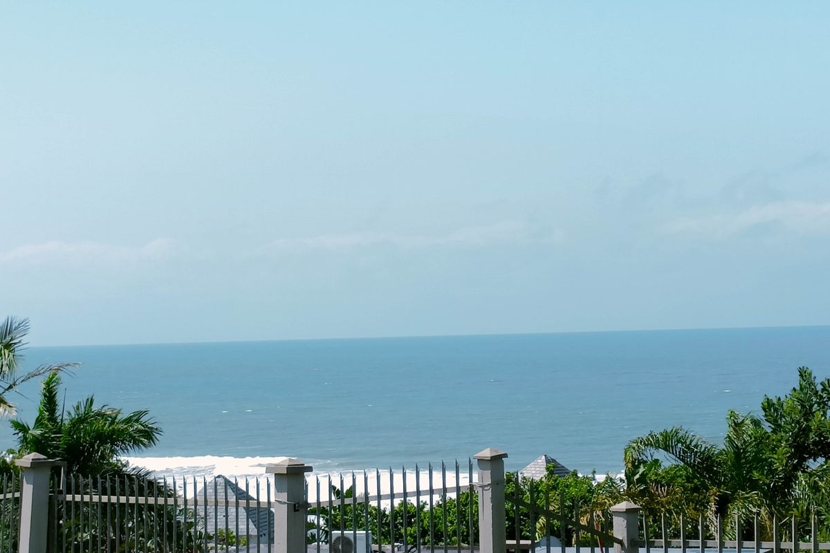 A scenic ocean view captured from the property, featuring a clear horizon and metal perimeter fencing in the foreground.