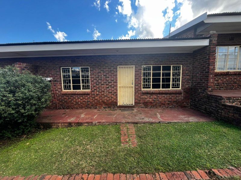 Front exterior view of a face brick apartment unit featuring a concrete patio, security gate, and steel-framed windows.