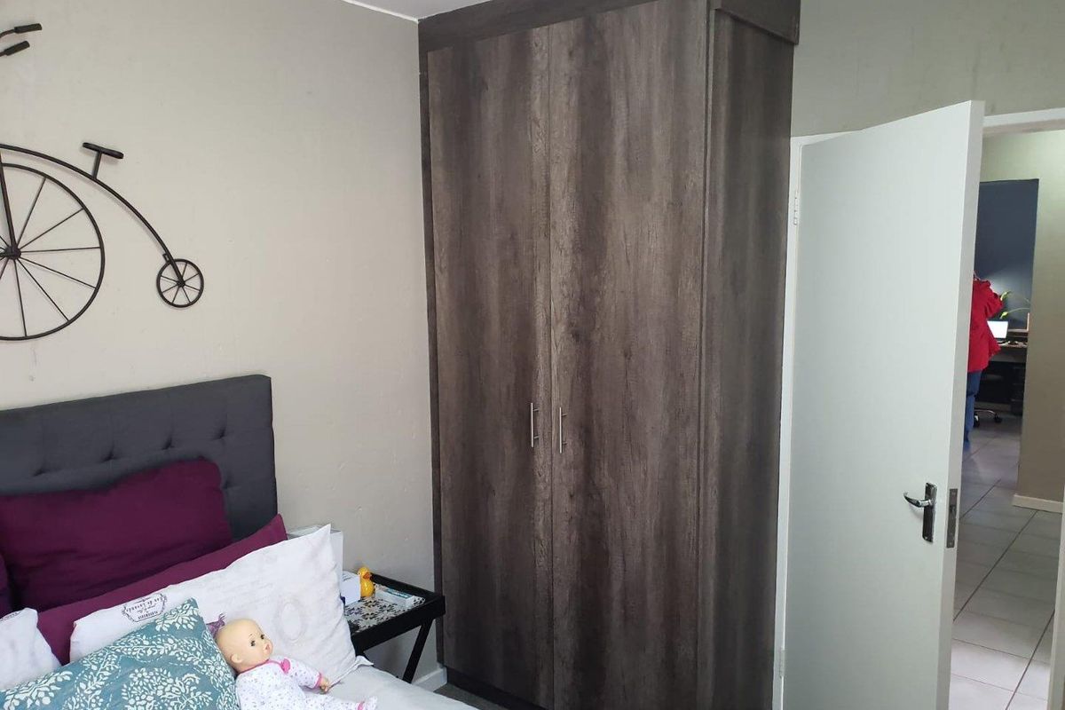 A bedroom featuring a dark wood-finish built-in wardrobe and a standard internal door leading to an adjacent room.