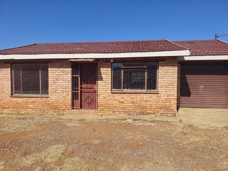 Front elevation of a face brick townhouse featuring a tiled roof, secure entrance with metal gate, and an integrated single garage.