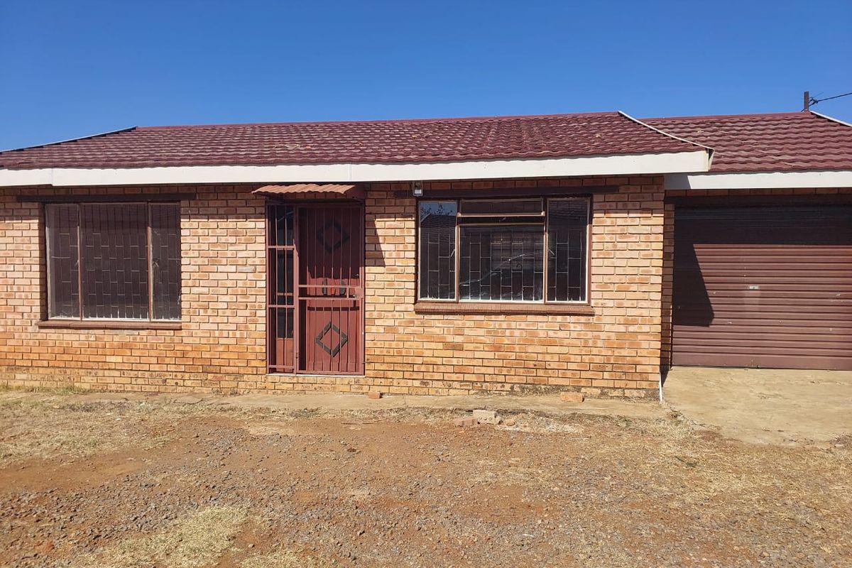 Front elevation of a face brick townhouse featuring a tiled roof, secure entrance with metal gate, and an integrated single garage.