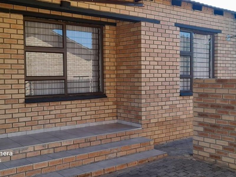 Front exterior view of the apartment featuring face brick construction, tiled entrance steps, and secure aluminium window frames.