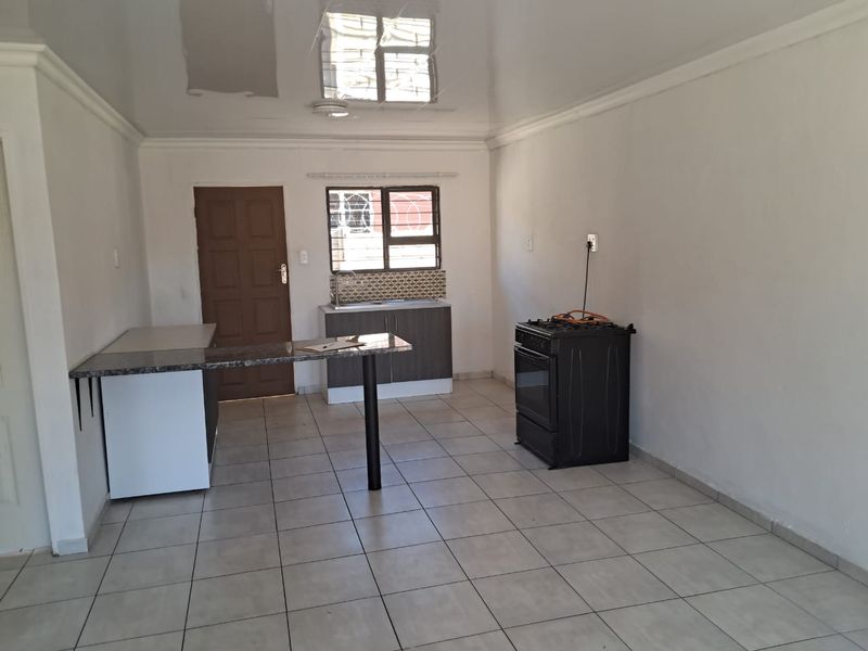 Open plan living and kitchen area featuring tiled floors, built-in cabinetry with granite countertops, a breakfast bar, and a gas stove.