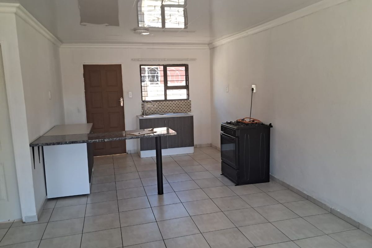 Open plan living and kitchen area featuring tiled floors, built-in cabinetry with granite countertops, a breakfast bar, and a gas stove.