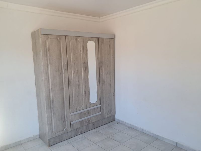 A simple bedroom featuring tiled flooring and classic ceiling cornicing, providing a clean and neutral space ready for personalization.